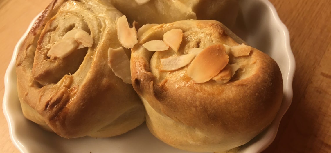 Hefeschnecken - drei frisch gebackene finnische Pulla auf einem Teller.