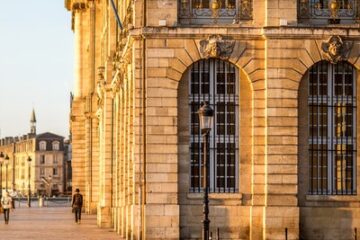Uferpromenade an der Garonne in Bordeaux mit klassischer Steinfassade und Kirchturm im Hintergrund