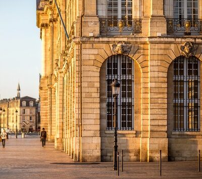 Uferpromenade an der Garonne in Bordeaux mit klassischer Steinfassade und Kirchturm im Hintergrund