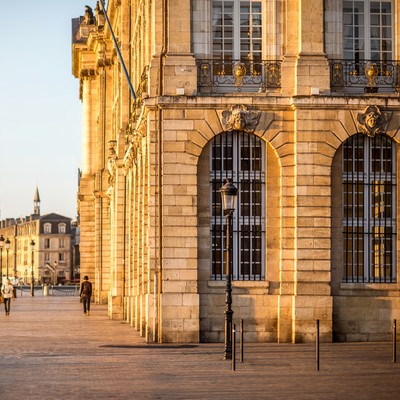 Uferpromenade an der Garonne in Bordeaux mit klassischer Steinfassade und Kirchturm im Hintergrund